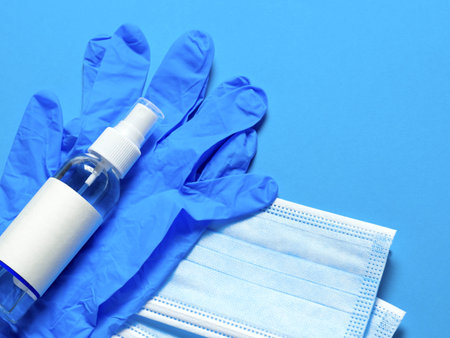 Medical protective mask, latex gloves, hand sanitizer on a blue background. Individual, disposable...