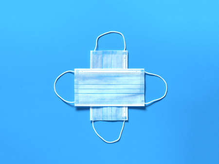 Medical protective mask on a blue paper background. Individual, disposable surgical face mask flat lay pattern. Quarantine healthcare, hygiene and coronavirus protection concept background.の写真素材