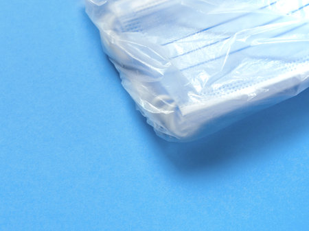 Pack of medical protective masks on a blue paper background. Individual, disposable surgical face...