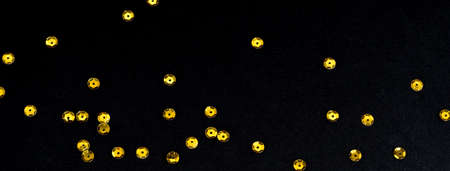Golden paillette glitter on black background. Festive holiday bright backdrop. Social media banner or header.の写真素材