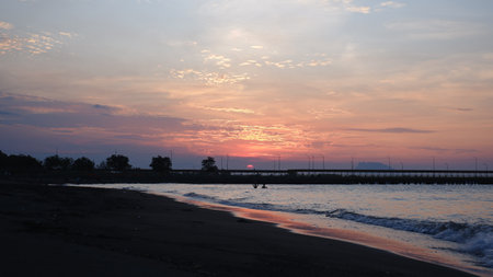View of the sky at dusk and the sun will set on the beach with the silhouette of the bridge in the harbor.の写真素材