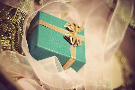 Holiday background with green gift box with gold bow among pink ribbons.の写真素材