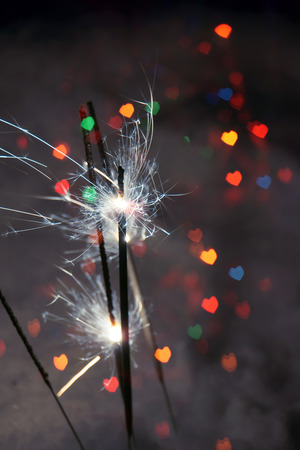 Bengal fire, sparkler and colorful bokeh in a shape of a heart, holiday background.の写真素材