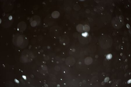 Snowfall in the winter evening, blurry natural background.の写真素材