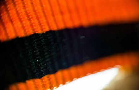 Macro photo of black orange strip ribbon tape, St. George ribbon, abstract blurry background.の写真素材
