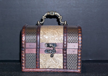 Close up of a decorative wooden box chest on dark background.