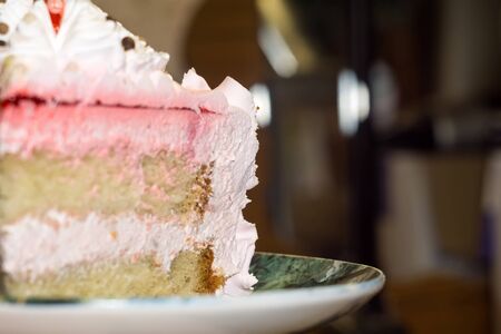 Macro of tasty cake with white, pink cream and chocolate decorations.の写真素材