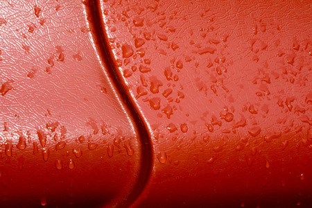Bright red metal roof surface with water drops.の写真素材
