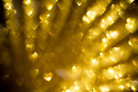 Festive background with defocused golden glitters, bokeh in a shape of a heart.
