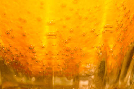 Fresh orange fruit slice in a glass of soda water, macro background.の写真素材