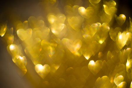 Festive background with defocused golden glitters, bokeh in a shape of a heart.