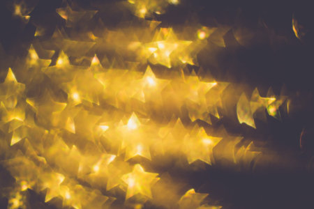 Festive background with defocused golden glitters, bokeh in a shape of a star.