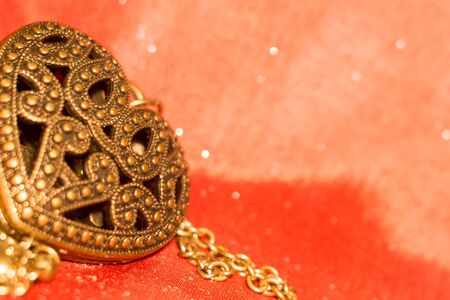 Vintage big heart shaped pendant on silk fabric background.の写真素材