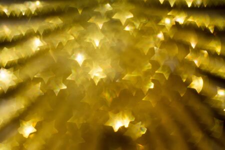 Festive background with defocused golden glitters, bokeh in a shape of a star.の写真素材