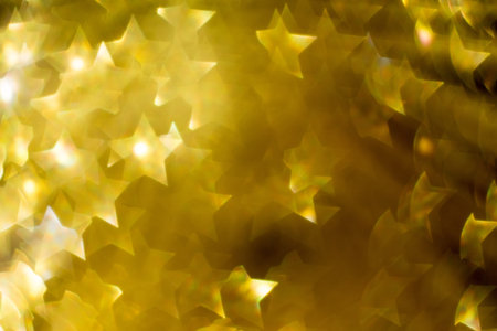 Festive background with defocused golden glitters, bokeh in a shape of a star.