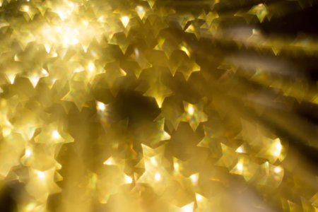 Festive background with defocused golden glitters, bokeh in a shape of a star.