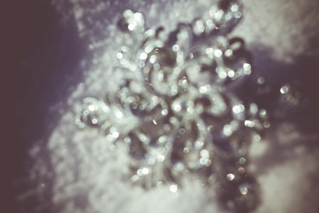 Defocused Ornamental silver snowflake glittering on fresh white snow, filtered retro colors.の写真素材