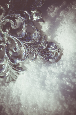 Ornamental silver snowflake glittering on fresh white snow, filtered retro colors.の写真素材