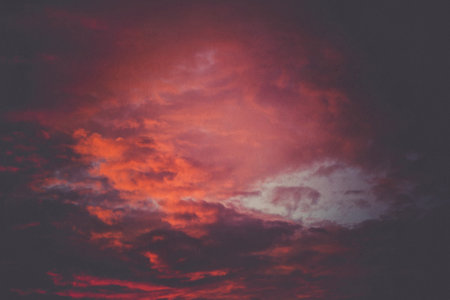 Summer sky with orange and purple clouds at sunset time, retro textured background.