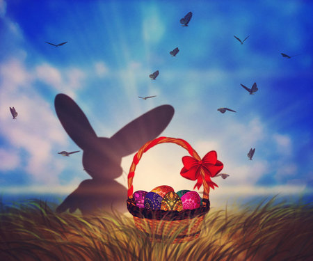 Sunny grassfield and Easter basket full of colored eggs.