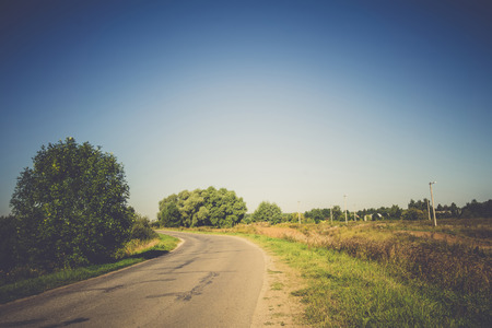 Old cracked, damaged asphalt road in countryside, vintage colors.の写真素材