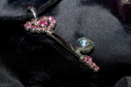 Silver pendant heart shaped key, made with pink crystal stones macro.