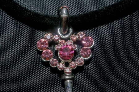 Silver pendant heart shaped key, made with pink crystal stones macro.の写真素材