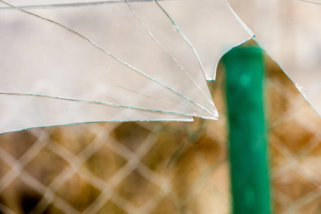 Sharp glass hole cracks splinters, broken glass by the street.