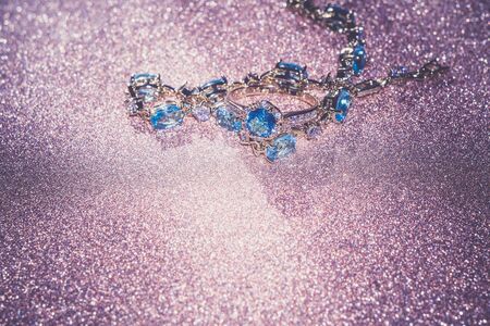 Decorative golden bracelet with light blue topaz on glittering background.の写真素材