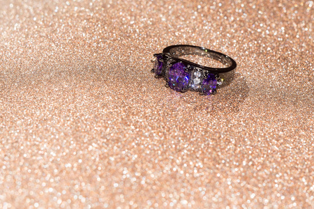 Fashion black gold ring with purple amethyst on glittering background.の写真素材