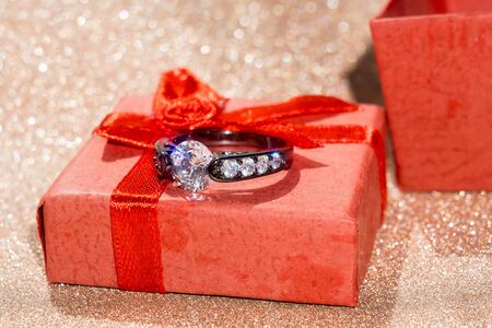 Diamond ring of black gold in a red gift box on glittering background.の写真素材