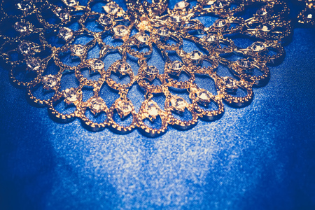 Elegant golden necklace with jewel stones on a background of blue silk, vintage background.の写真素材