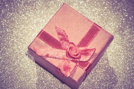 Decorative red gift box with bow on glittering background.の写真素材