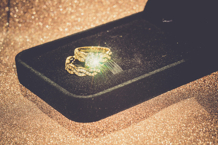 Diamond ring in a black gift box on glittering background.の写真素材