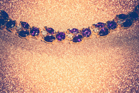 Decorative golden bracelet with purple amethysts on glittering background.の写真素材