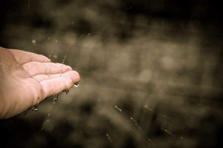 Splashing drops of rain on human palm, close up background.の写真素材