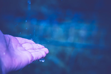 Splashing drops of rain on human palm, close up background.