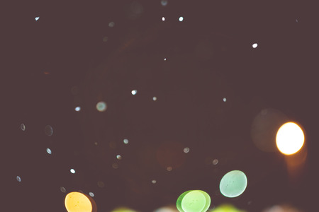 Blurred night lights and snowfall, bokeh effect filtered background.の写真素材