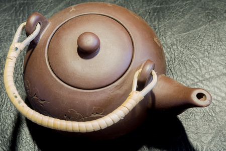 Brown chinese clay teapot close up on black leather background.の写真素材
