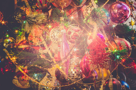 Close up of Christmas or New Year fir tree with decorative lights and toys, filtered background.