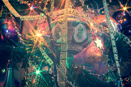 Close up of Christmas or New Year fir tree with decorative lights and toys, filtered background.