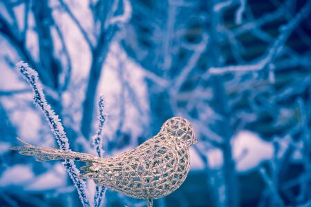 Decorative element artificial glittering golden bird, ornamental Christmas toy, filtered background.の写真素材