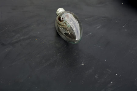 Old incandescent light bulb on dark background.