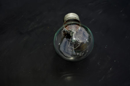 Old incandescent light bulb on dark background.
