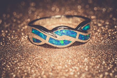 Fashion ring decorated with blue fire opal stones, filtered background.の写真素材