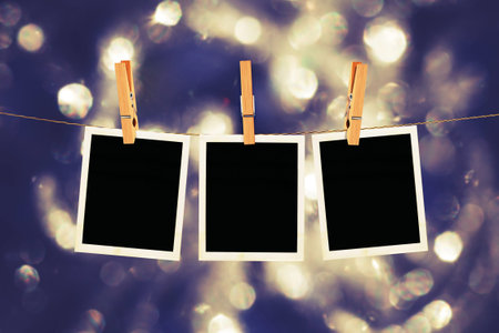 Old photo film blanks hanging on a rope held by clothespins on bokeh lights background.