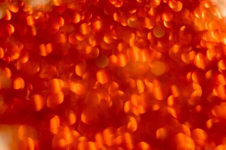 Defocused glitter as background with circular bokeh of red color.の写真素材