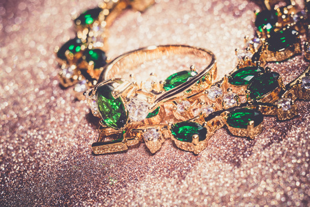 Elegant female jewelry golden bracelet with precious green gem, emerald, retro background.の写真素材