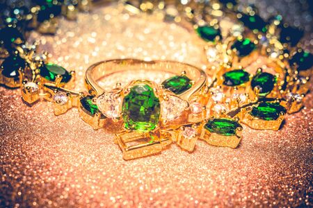 Elegant female jewelry golden ring with precious green gem, emerald, filtered background.の写真素材