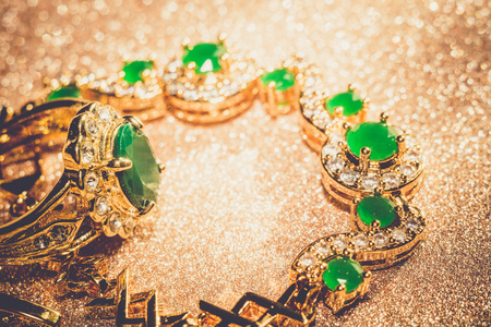Elegant female jewelry golden bracelet with precious green gem, emerald, retro background.の写真素材
